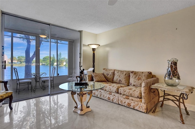 living room featuring light tile floors, a water view, expansive windows, and a textured ceiling