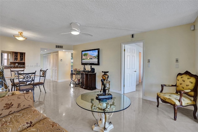 tiled living room with ceiling fan and a textured ceiling