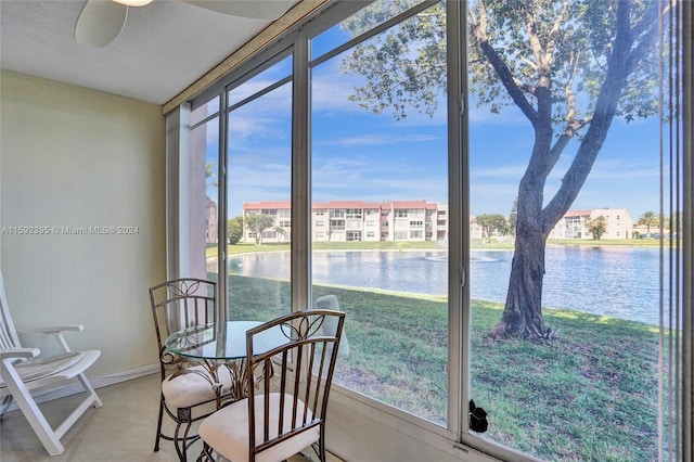 sunroom with a healthy amount of sunlight, ceiling fan, and a water view