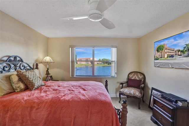 bedroom featuring ceiling fan, a textured ceiling, and a water view