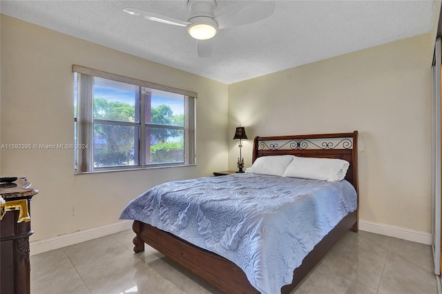 tiled bedroom with ceiling fan and a textured ceiling