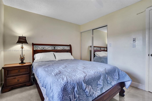 bedroom featuring a closet, a textured ceiling, and light tile floors