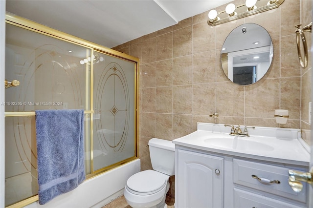 full bathroom with shower / bath combination with glass door, tile floors, toilet, tile walls, and oversized vanity