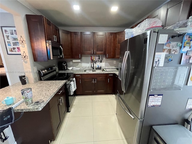 kitchen with sink, light stone counters, light tile patterned floors, ornamental molding, and stainless steel appliances