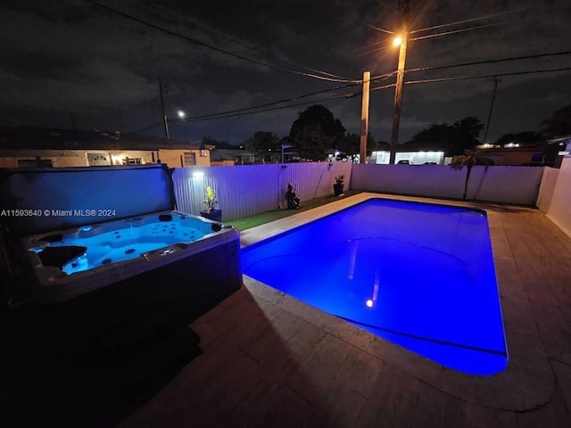 pool at night with an in ground hot tub