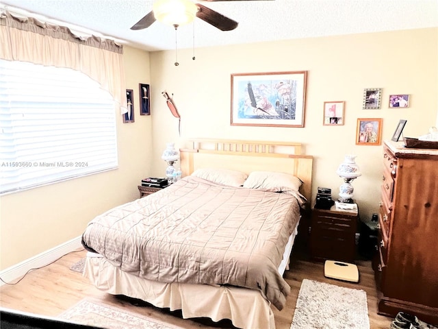 bedroom featuring wood-type flooring, ceiling fan, and a textured ceiling