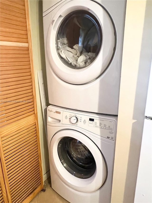 laundry room featuring stacked washer / dryer and tile flooring