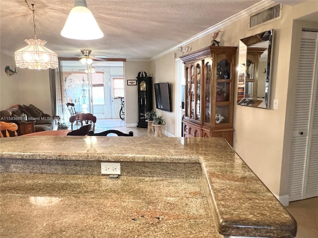 kitchen featuring hanging light fixtures, a textured ceiling, ornamental molding, ceiling fan with notable chandelier, and tile floors