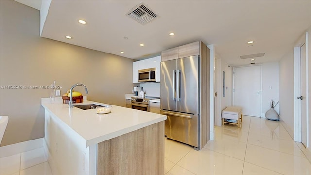 kitchen with light brown cabinets, stainless steel appliances, sink, and kitchen peninsula