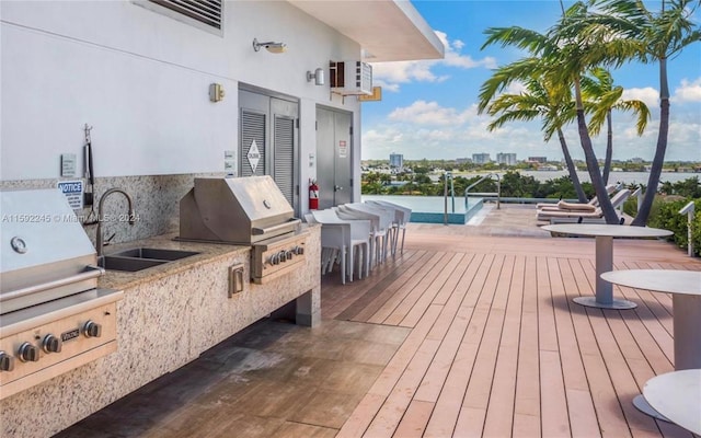 wooden terrace featuring an outdoor kitchen, a grill, and sink