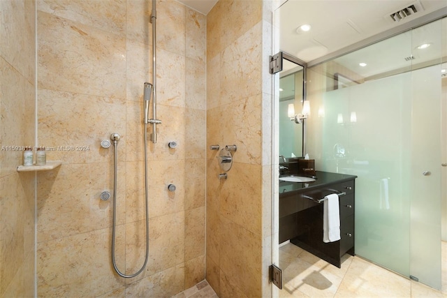 bathroom with a tile shower, vanity, and tile floors