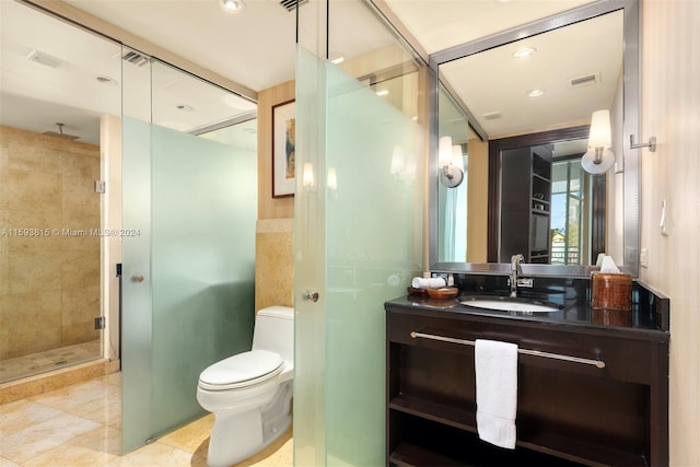 bathroom with vanity, toilet, tile floors, and a shower with door