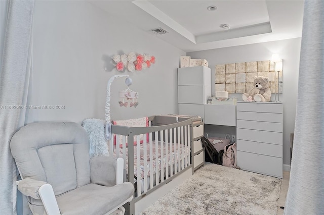 bedroom featuring a raised ceiling, white fridge, and a nursery area