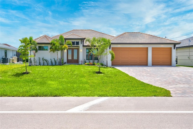 view of front of house with a garage, a front yard, central AC unit, and french doors