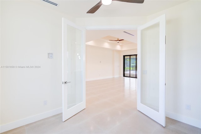 empty room featuring french doors, ceiling fan, and a raised ceiling