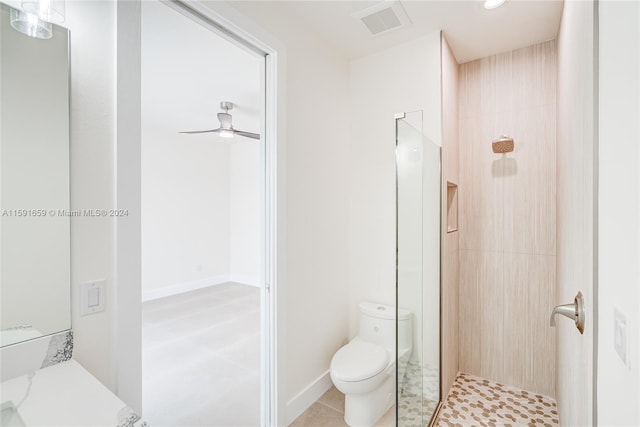 bathroom featuring ceiling fan, toilet, and tiled shower