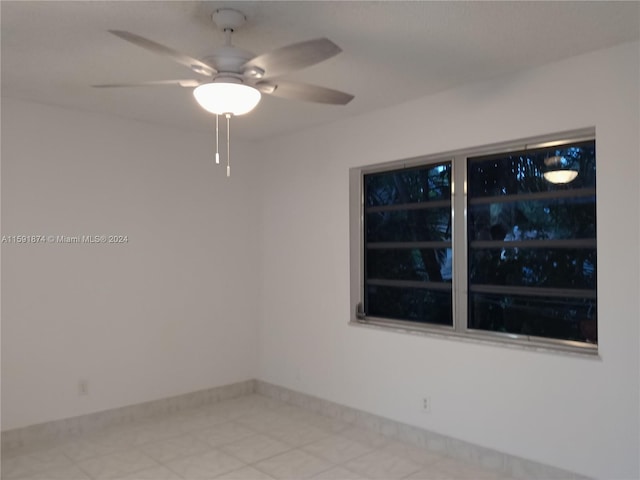 empty room with ceiling fan and light tile patterned floors