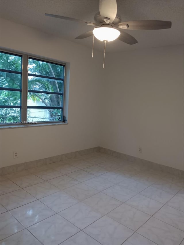 empty room with light tile patterned floors and ceiling fan