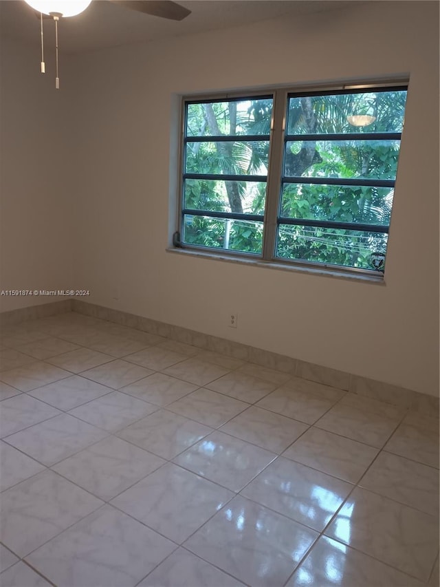 tiled spare room with ceiling fan