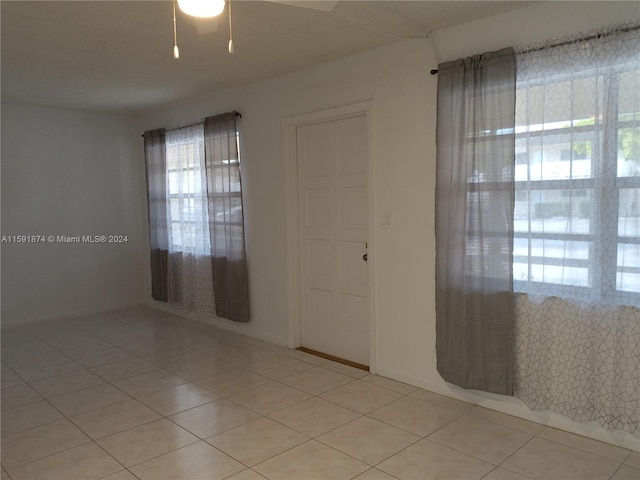 tiled spare room with ceiling fan