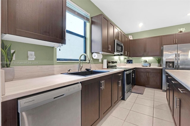 kitchen featuring light tile patterned flooring, dark brown cabinetry, sink, and appliances with stainless steel finishes