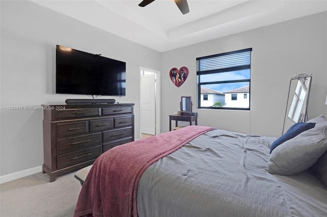 carpeted bedroom with a tray ceiling and ceiling fan