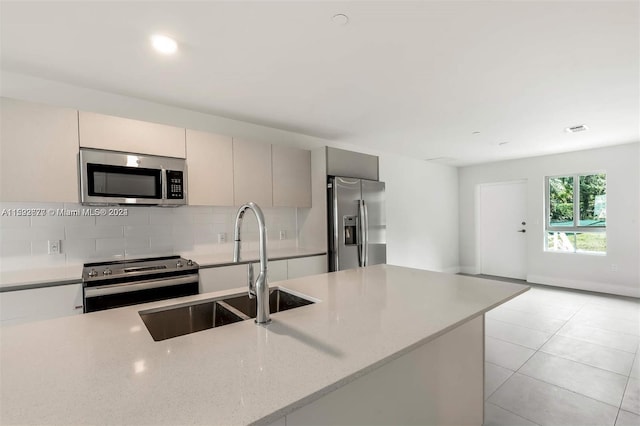 kitchen with stainless steel appliances, light stone counters, sink, tasteful backsplash, and light tile floors