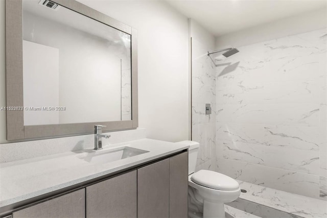 bathroom featuring tiled shower, toilet, and vanity