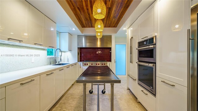 kitchen with tasteful backsplash, light tile patterned floors, wall chimney exhaust hood, wooden ceiling, and sink