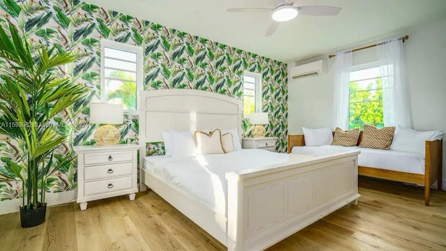 bedroom featuring light hardwood / wood-style floors, an AC wall unit, and ceiling fan