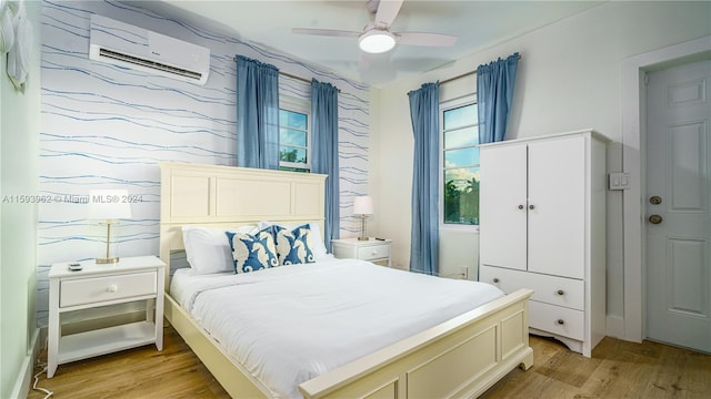 bedroom featuring light hardwood / wood-style flooring, a wall unit AC, and ceiling fan