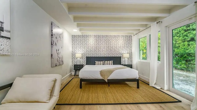 bedroom with beamed ceiling, a fireplace, and hardwood / wood-style flooring