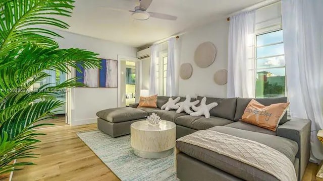 living area featuring hardwood / wood-style flooring, a wall mounted air conditioner, and ceiling fan