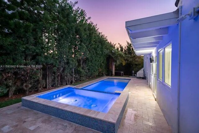 pool at dusk featuring a patio