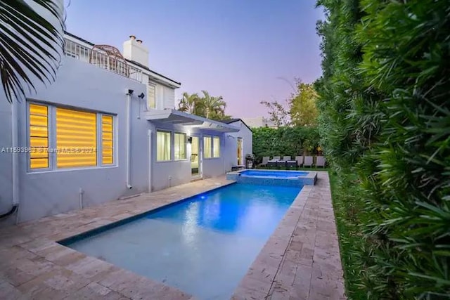 pool at dusk with a patio area