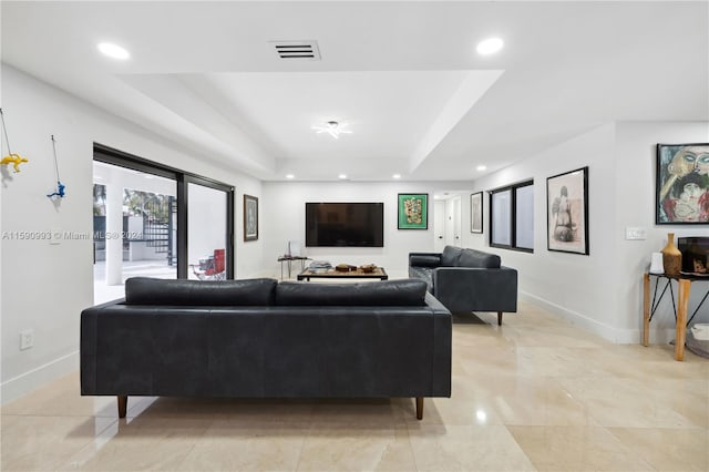 tiled living room with a raised ceiling and french doors