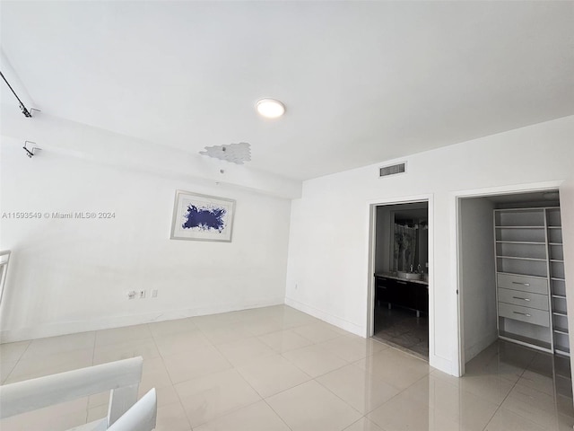 unfurnished bedroom featuring a walk in closet, a closet, and light tile patterned floors