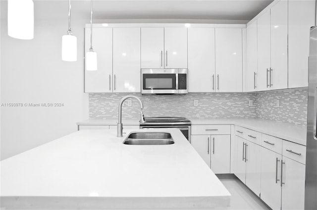 kitchen featuring tasteful backsplash, white cabinetry, appliances with stainless steel finishes, hanging light fixtures, and sink