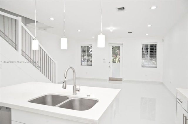 kitchen featuring a center island with sink, white cabinetry, sink, and pendant lighting