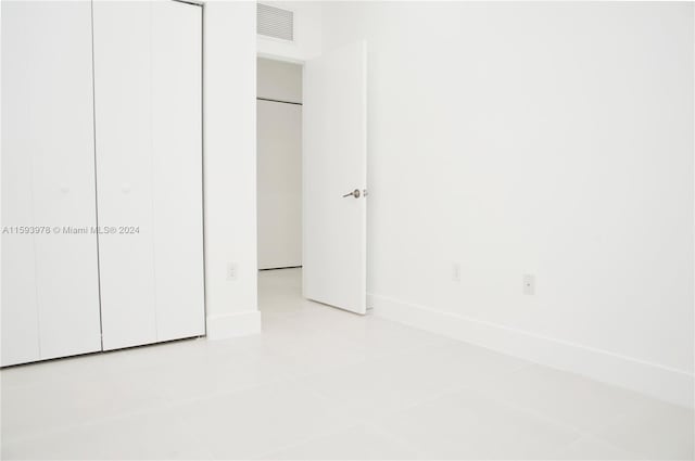 unfurnished bedroom with light tile patterned flooring and a closet