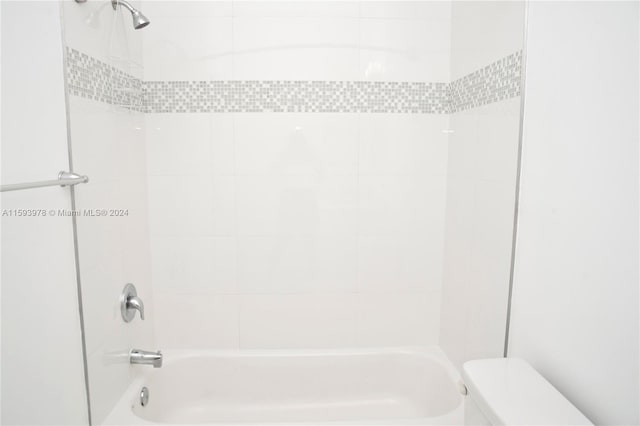 bathroom featuring tiled shower / bath combo and toilet