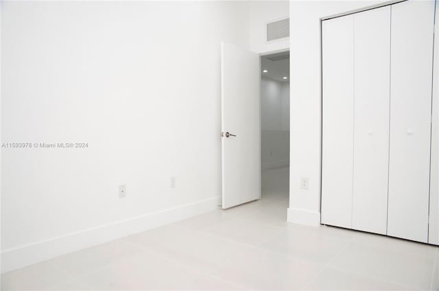 unfurnished bedroom featuring light tile patterned floors and a closet