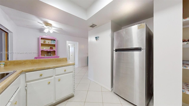 kitchen with white cabinetry, light tile patterned floors, stainless steel refrigerator, and ceiling fan