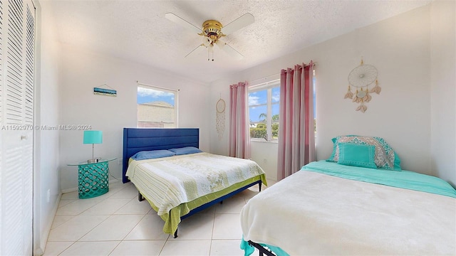 bedroom with ceiling fan, a closet, a textured ceiling, and light tile patterned flooring