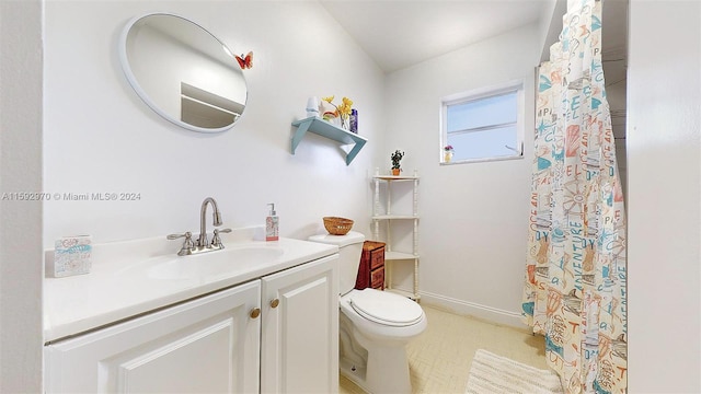 bathroom with toilet, vanity, and tile patterned floors