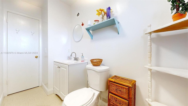 bathroom with toilet, vanity, and tile patterned floors