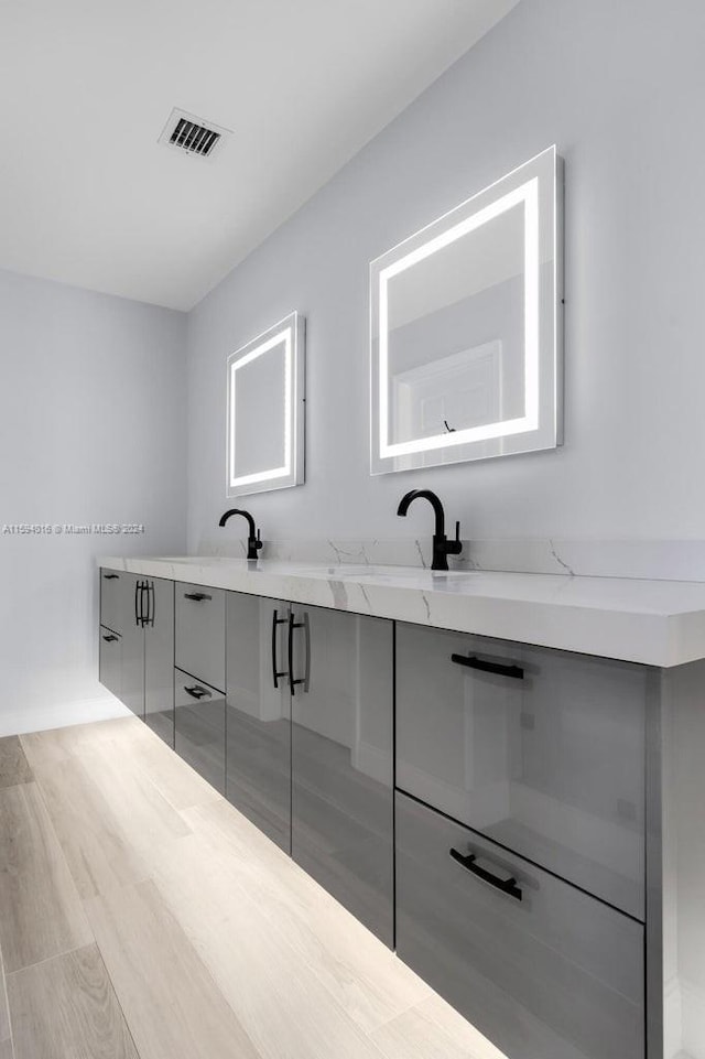 bathroom with dual bowl vanity and hardwood / wood-style floors