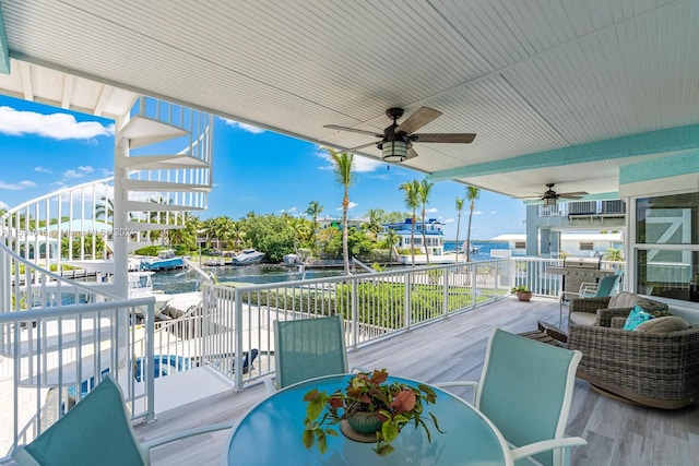 deck with ceiling fan and a water view