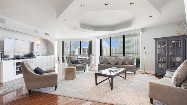 living room with a raised ceiling and light hardwood / wood-style flooring