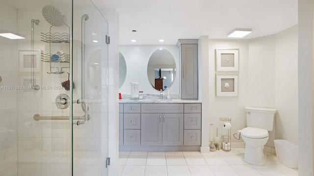 bathroom featuring a shower with door, tile flooring, vanity, and toilet